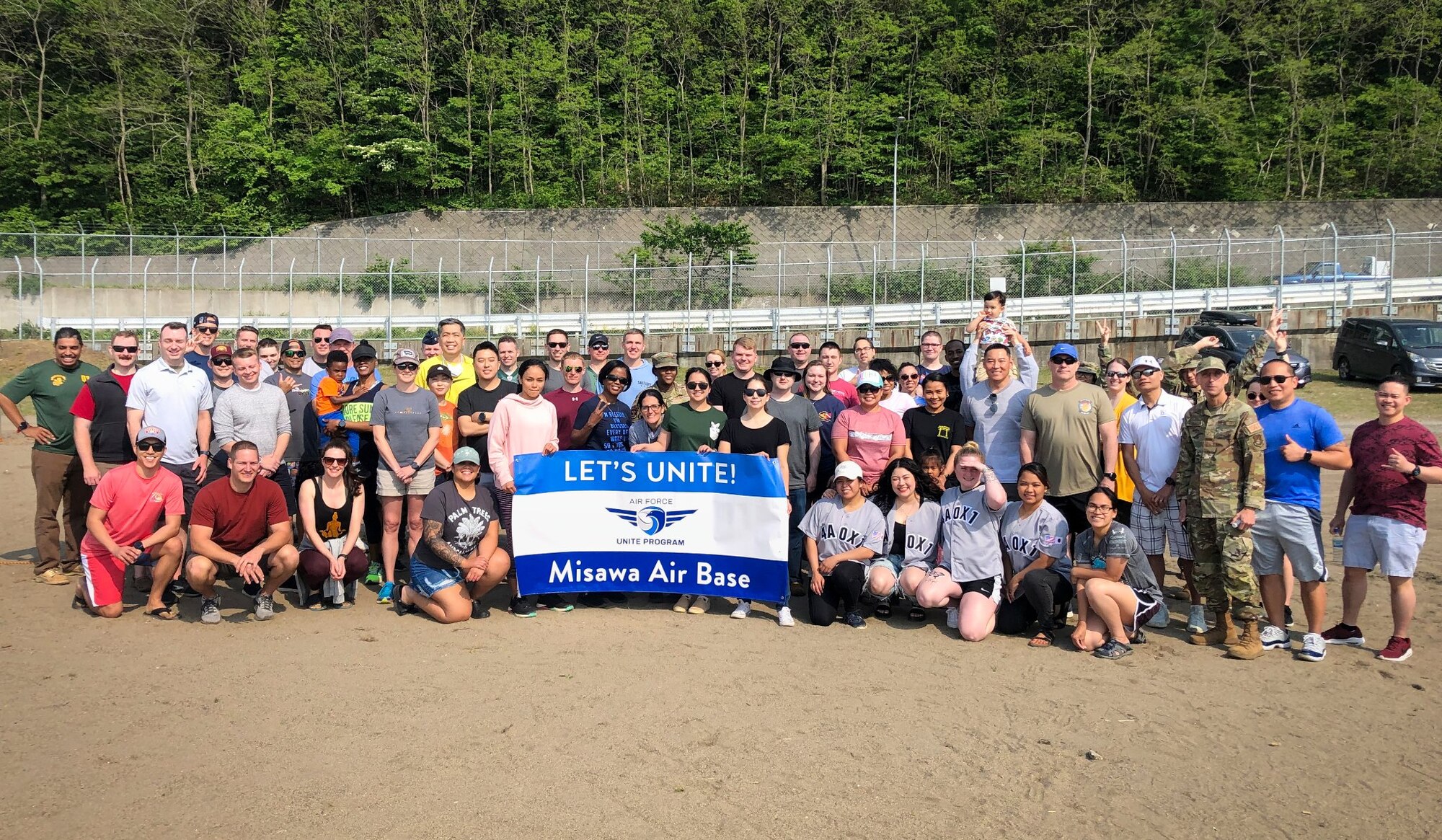 Members stand on a beach holding a sign