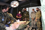 U.S. Ambassador Herro Mustafa, Bulgarian Army Col. Ivan Popivanov, Bulgarian Air Force Col. Dimo Dimov, and U.S. Army Col. Keith Evans, observe a simulated battalion aid station at a medical tent in the Bulgarian Military Medical Simulation Training Center in Sofia, Bulgaria, 10 August, 2022.