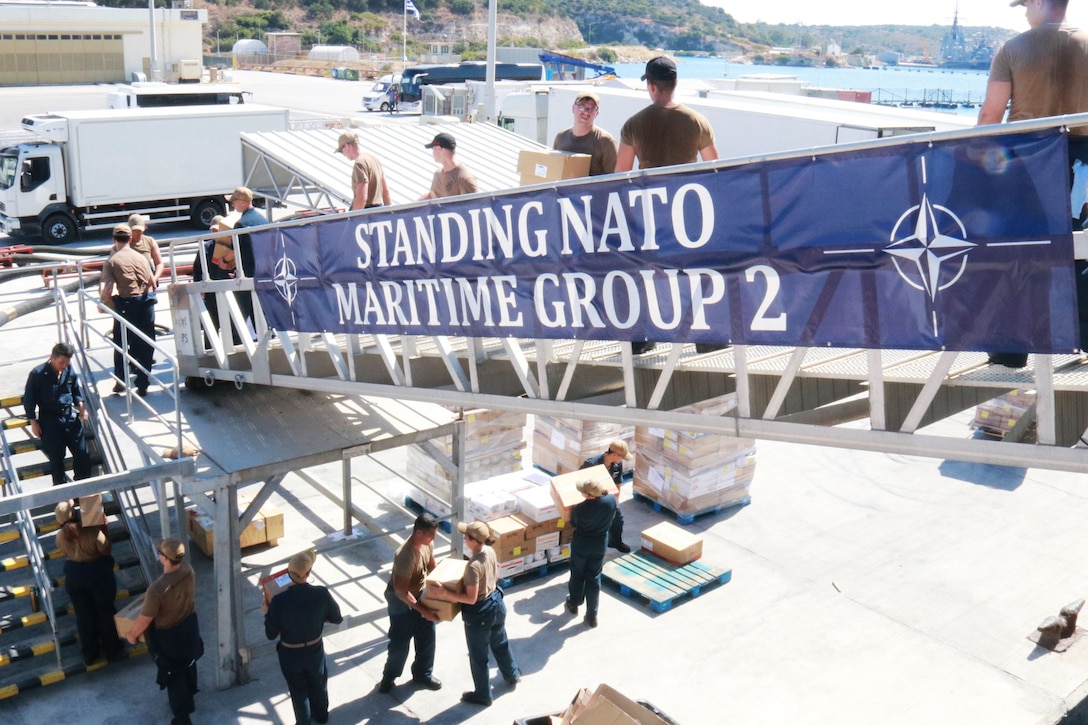 Service members carry boxes down a ramp.