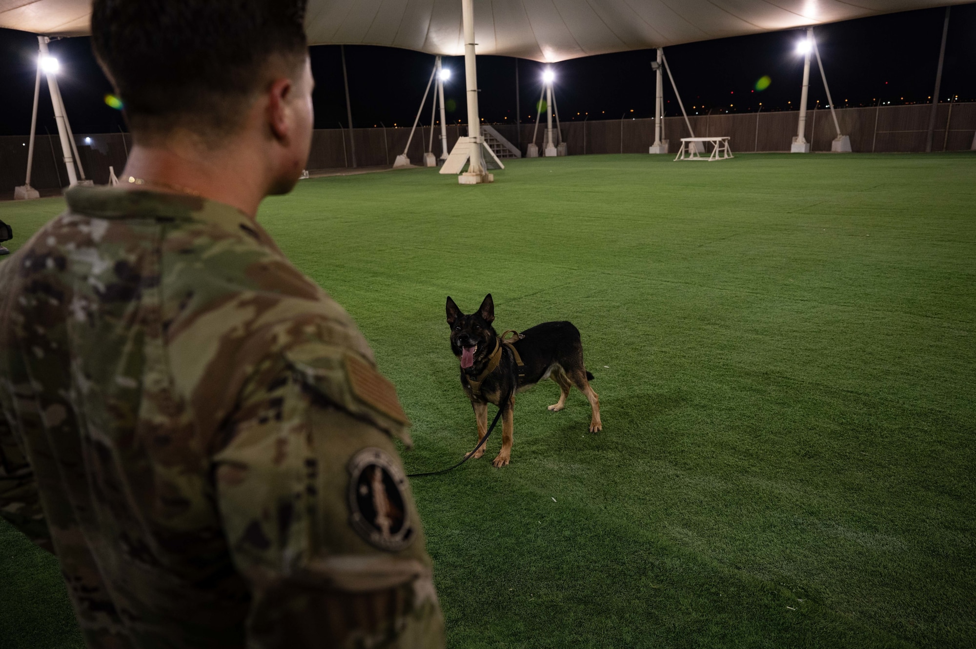 U.S. Air Force Staff Sgt. Justin Pickens, a military working dog handler with the 379th Expeditionary Security Forces Squadron, works with his dog MWD Gyozo at Al Udeid Air Base, Qatar, on AUG 10, 2022. Gyozo was supposed to be taking a water break but he was too excited to get back to training on the course. (U.S. Air Force photo by Staff Sgt. Dana Tourtellotte)
