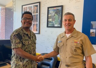 Fire Controlman 2nd Class Marvin Tilghman, left, poses for a photo with Rear Adm. Pete Garvin, commander, Naval Education and Training Command (NETC), at Navy Recruiting Station Woodbridge, Virginia, Aug. 16, 2022.
