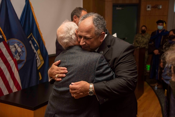 Secretary of the Navy Carlos Del Toro, right, embraces Professor Emeritus Dr. Rudy Panholzer, Del Toro's former professor and thesis advisor, during an award ceremony Aug. 18, 2022. Del Toro awarded Panholzer with the Distinguished Civilian Service Award for his life-long commitmne to the Naval Postgraduate School and to the DOD at large.