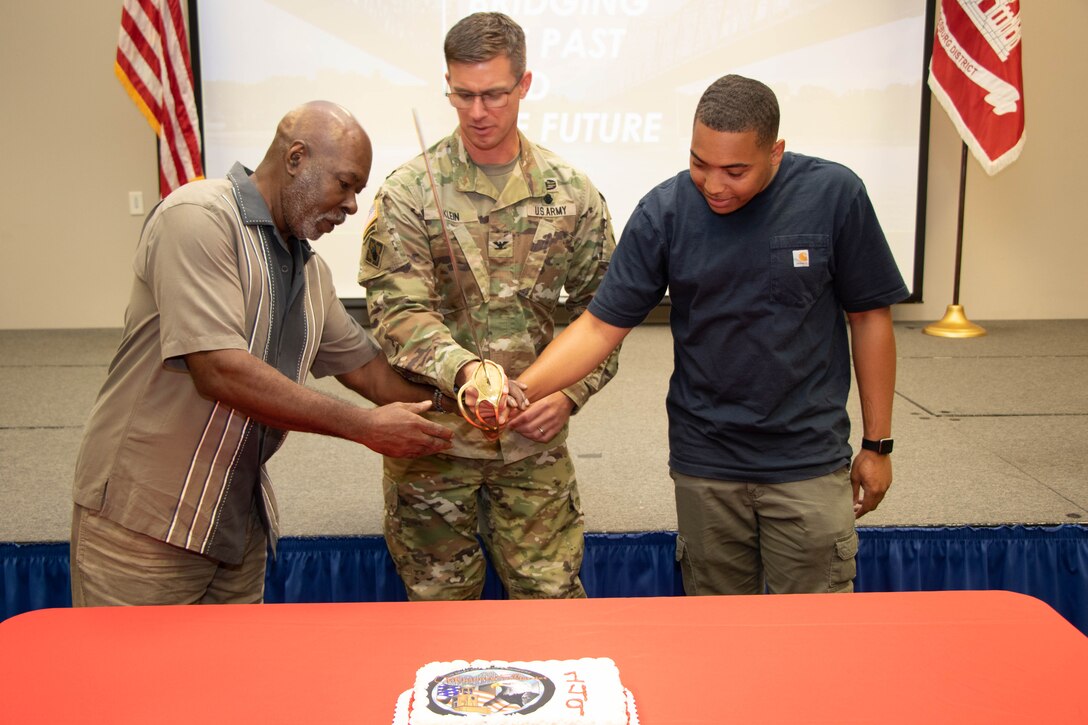 Vicksburg District commander COL Christopher Klein cuts the ceremonial cake for the 2022 Founders Day event. He is joined by the most senior and most junior employees in the District.