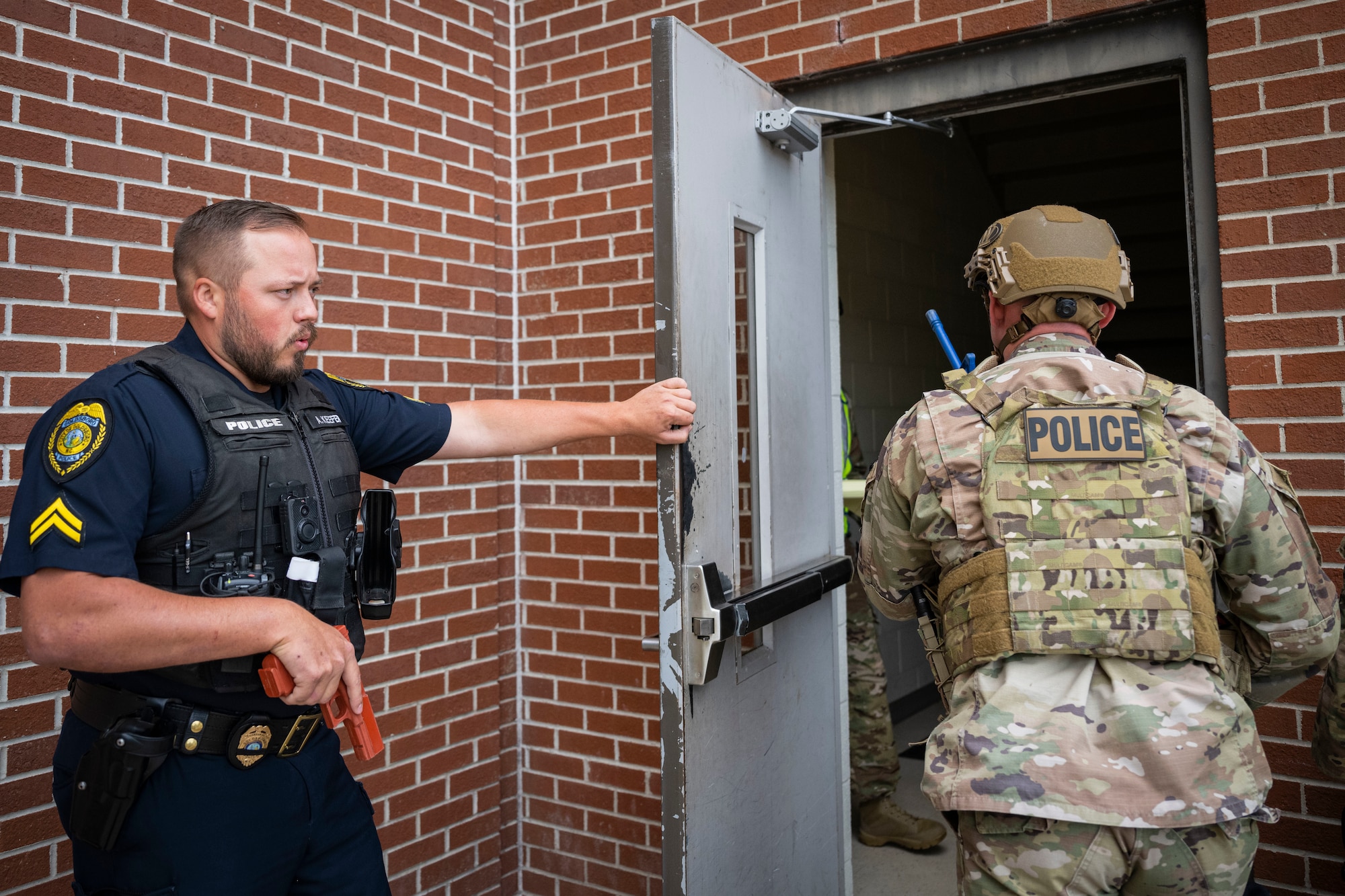 A member of the Goldsboro Police Department holds a door for an Airman assigned to the 4th Security Forces Squadron during an active shooter exercise at Seymour Johnson Air Force Base, North Carolina, Aug. 19, 2022. The Goldsboro PD worked jointly with the 4th SFS during the exercise.