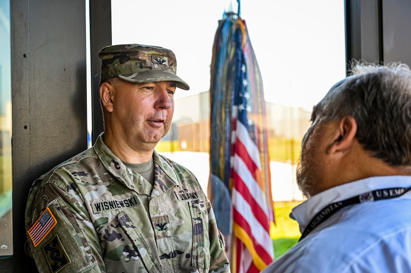 U.S. Army Col. Mitchell Wisniewski, Joint Base McGuire-Dix-Lakehurst deputy commander, and Army Support Activity Fort Dix commander, speaks with a guest at the Army Support Activity Fort Dix Aviation Facility ribbon cutting ceremony at Joint Base McGuire-Dix-Lakehurst N.J. on Aug. 19, 2022. The Army Aviation Facility Project was a MILCON effort valued at 11.7 million dollars and made possible through the joint effort of ASA Fort Dix and the U.S. Marine Corps Marine Aircraft Group 49. The 2100 square foot building is host to an Army Ramp Management Area which provides a wide range of capabilities for both fixed and rotary wing aircraft such as the C-130, CH-47S, and UH-60S. The addition of the new Army Ramp will provide enhanced load out and aviation operation training capabilities, parking for Army aviation aircraft, refueling, troop movement and flight planning operations for approximately 216,000 people that use JB MDL to meet readiness requirements.