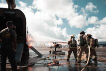 U.S. Marines assigned to Aircraft Rescue and Firefighting, Marine Corps Air Station Kaneohe Bay, extinguish the inside of a mock aircraft during a live-fire scenario at Landing Zone Westfield, Marine Corps Base Hawaii, Aug. 5, 2022. The ARFF Marines conducted the monthly training in order to enhance their firefighting skills in preparation of emergencies. (U.S. Marine Corps photo by Lance Cpl. Christian Tofteroo)