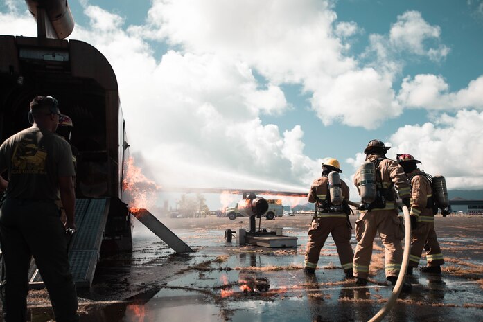 U.S. Marines assigned to Aircraft Rescue and Firefighting, Marine Corps Air Station Kaneohe Bay, extinguish the inside of a mock aircraft during a live-fire scenario at Landing Zone Westfield, Marine Corps Base Hawaii, Aug. 5, 2022. The ARFF Marines conducted the monthly training in order to enhance their firefighting skills in preparation of emergencies. (U.S. Marine Corps photo by Lance Cpl. Christian Tofteroo)