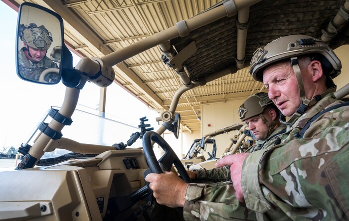 2 Royal Air Force Airmen sit in a vehicle.