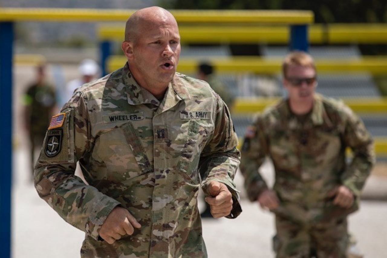 A soldier runs outside with another behind him.