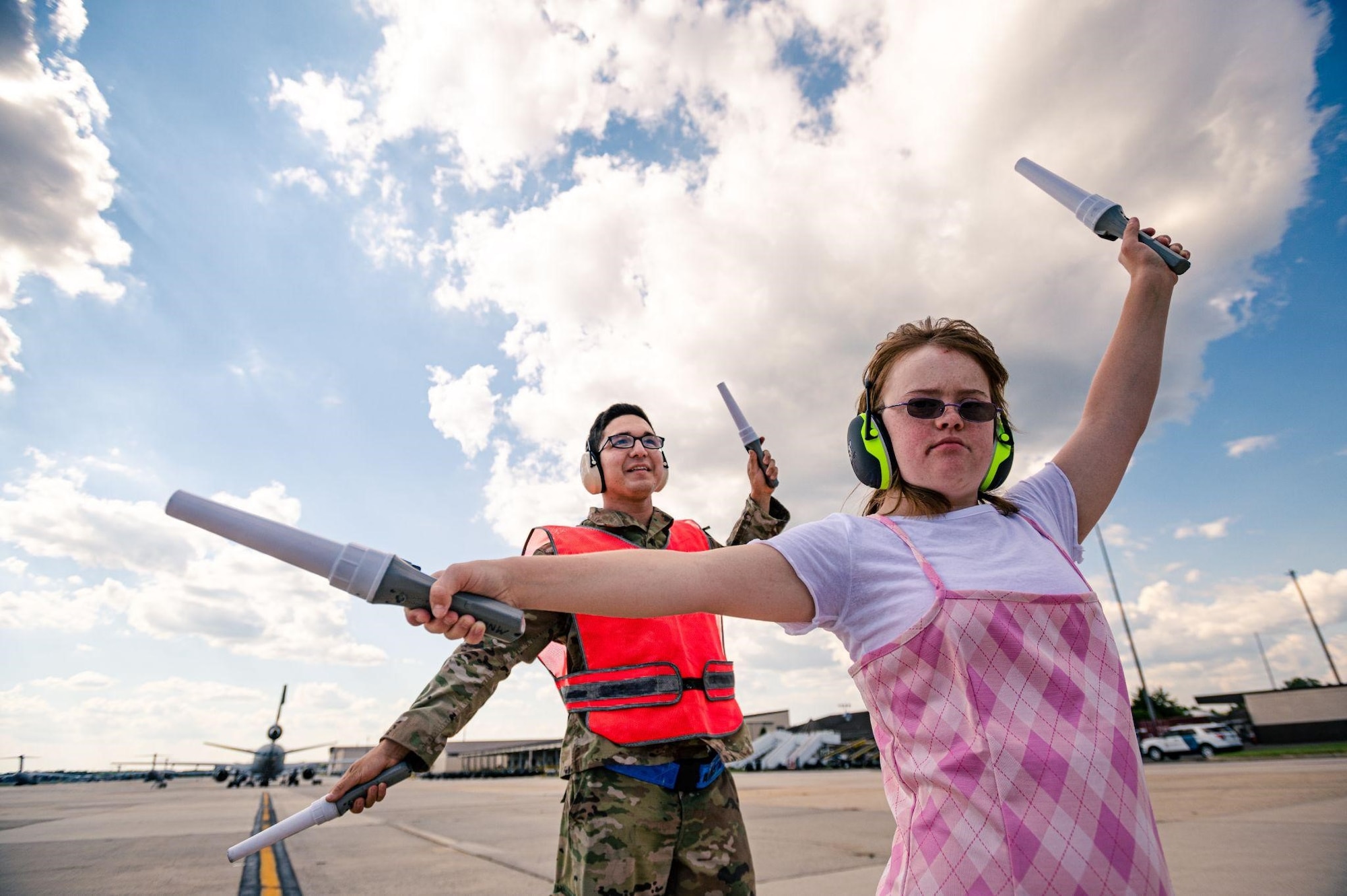 A girl and an airman marshal a plane