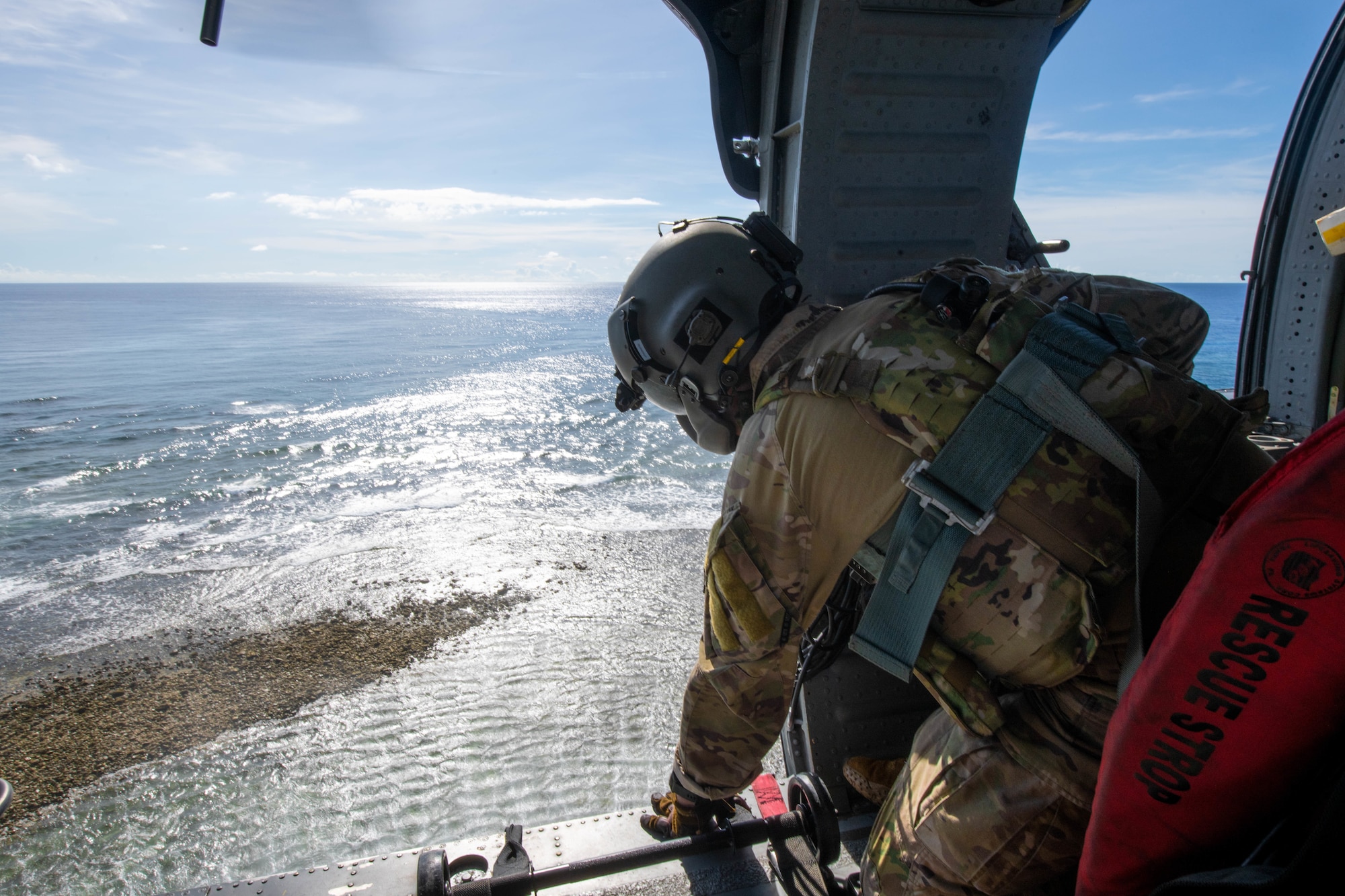 An Airman lets down a rope ladder from a hovering helicopter.
