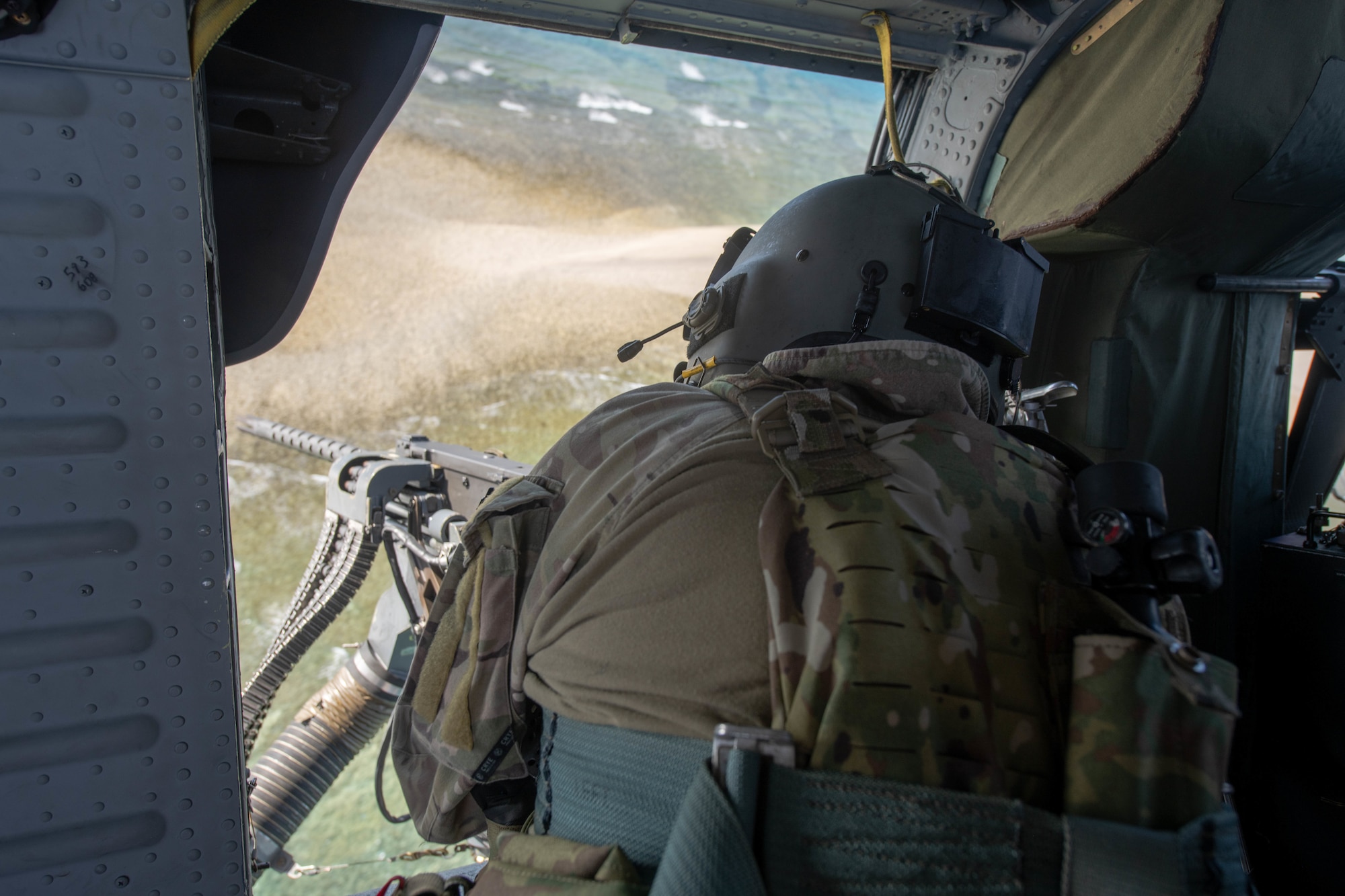 An Airman fires a door gun from a hovering helicopter.
