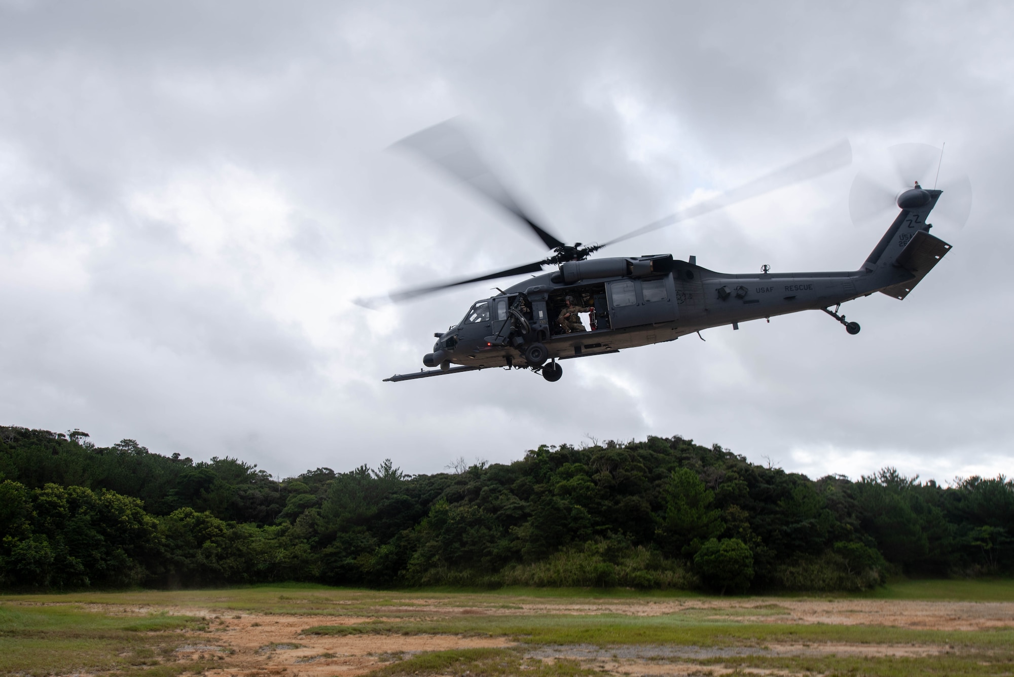 A helicopter lands in a clearing.