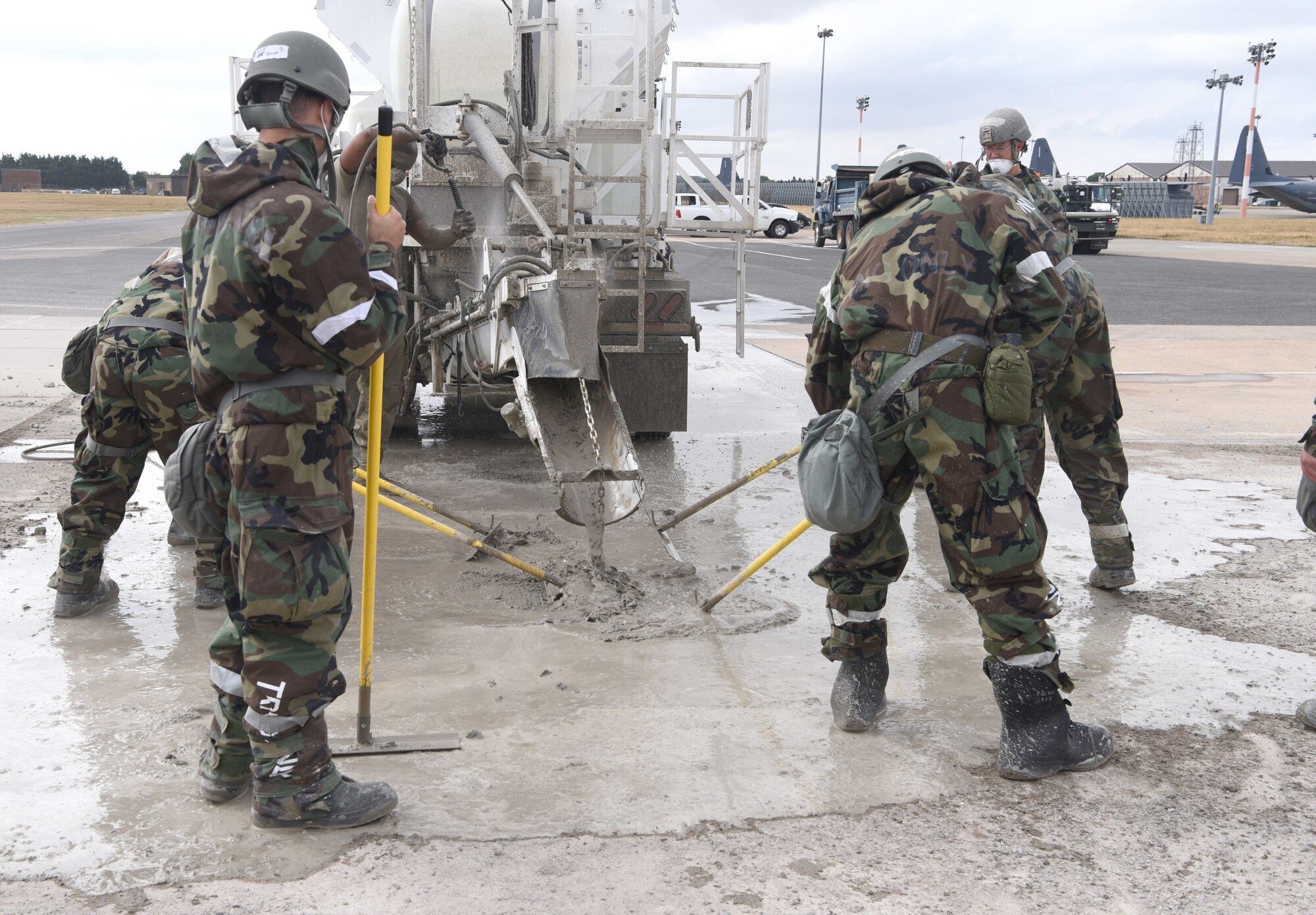 U.S. Air Force Airmen from the 100th Civil Engineer Squadron smooth out fast-drying concrete during a simulated damaged runway repair as part of a chemical, biological, radiological, nuclear and explosives exercise at Royal Air Force Mildenhall, England, Aug. 17, 2022. The 100th CES Airmen used a variety of equipment including excavators and loaders to practice removing damaged concrete and base course on a simulated runway. They practiced repair, break up and removal of concrete, before mixing and pouring new, quick-drying concrete and levelling it. (U.S. Air Force photo by Karen Abeyasekere)