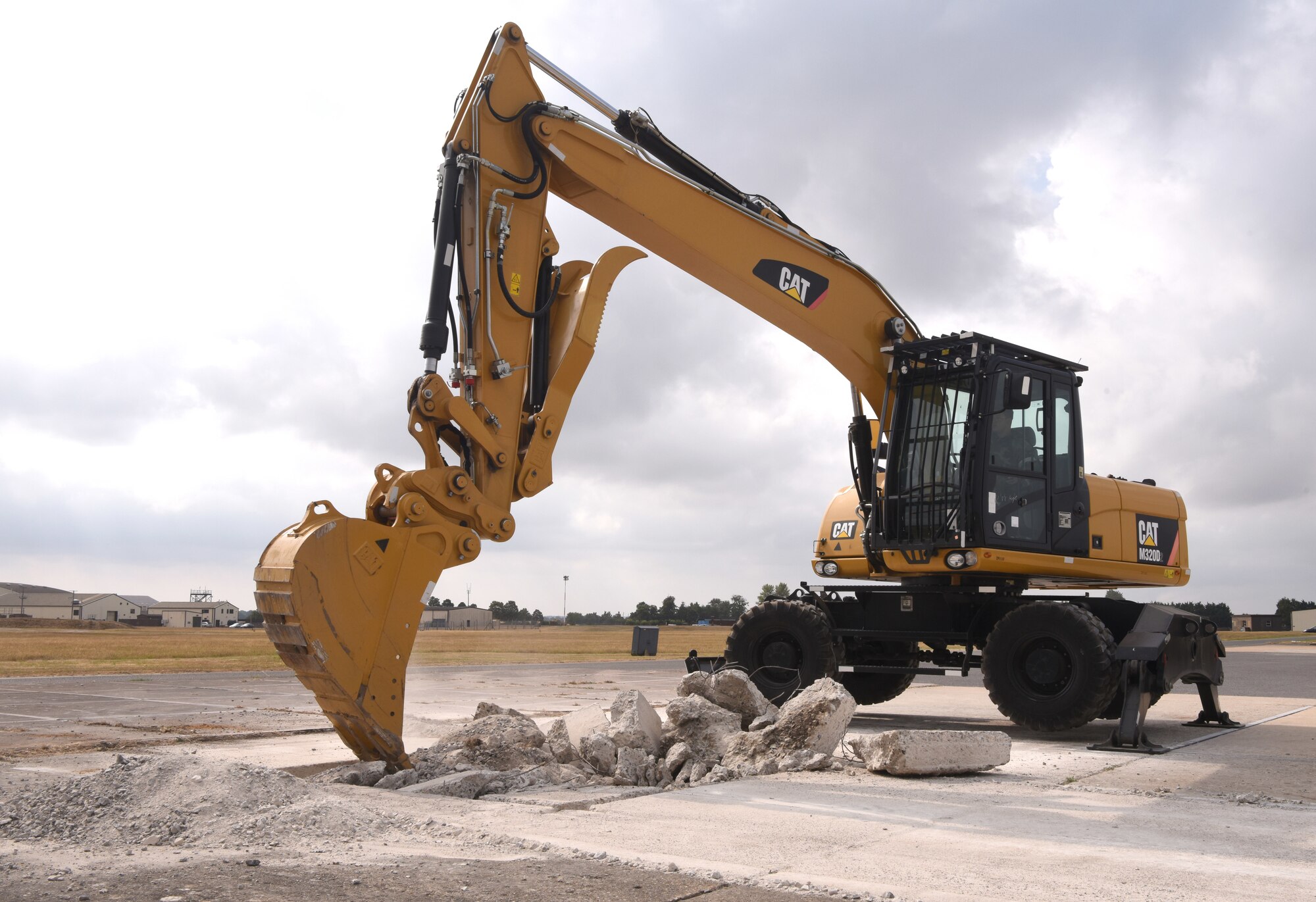 A U.S. Air Force 100th Civil Engineer Squadron Airman uses an excavator to clear concrete during a simulated runway repair as part of a chemical, biological, radiological, nuclear and explosives exercise at Royal Air Force Mildenhall, England, Aug. 17, 2022. The 100th CES Airmen used a variety of equipment including excavators and loaders to practice removing damaged concrete and base course on a simulated runway. They practiced repair, break up and removal of concrete, before mixing and pouring new, quick-drying concrete and levelling it. (U.S. Air Force photo by Karen Abeyasekere)