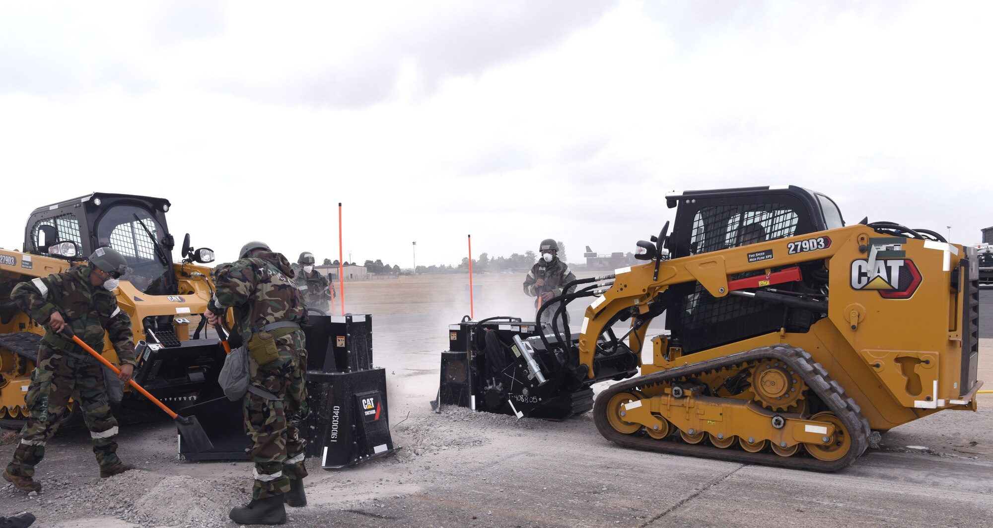 U.S. Air Force Airmen from the 100th Civil Engineer Squadron help clear broken concrete during a simulated runway repair as part of a a chemical, biological, radiological, nuclear and explosives exercise at Royal Air Force Mildenhall, England, Aug. 17, 2022. The Airmen used a variety of equipment including excavators and loaders to practice removing damaged concrete and base course on a simulated runway. They practiced repair, break up and removal of concrete, before mixing and pouring new, quick-drying concrete and levelling it, all while wearing mission-oriented protective postures gear. (U.S. Air Force photo by Karen Abeyasekere)