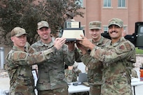 Four Airmen hold up a trophy