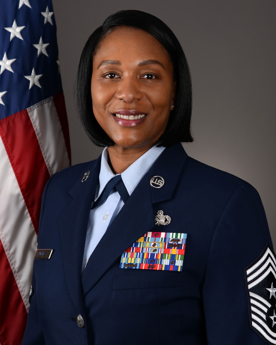 Official headshot photograph of new 55th Wing command chief with U.S. flag over right shoulder