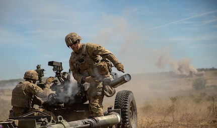 Pfc. Justin Schmitt (right), assigned to 1st Battalion, 134th Field Artillery Regiment, tosses the casing of a 105 mm artillery round during a direct fire exercise as part of Operation Northern Strike at Camp Grayling, Mich., Aug. 12, 2022.