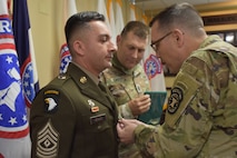 Soldier receives ribbon from Commander