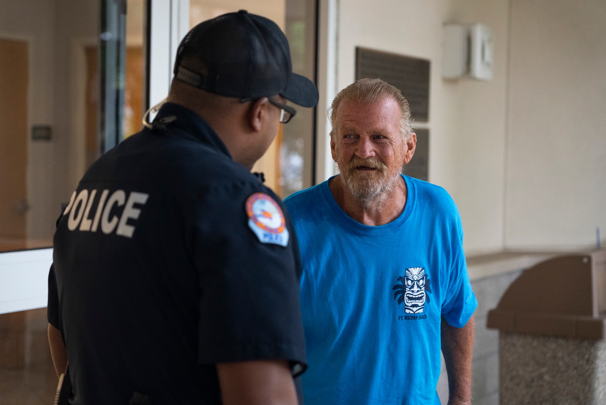 Older bearded man in blue shirt speaks with police officer