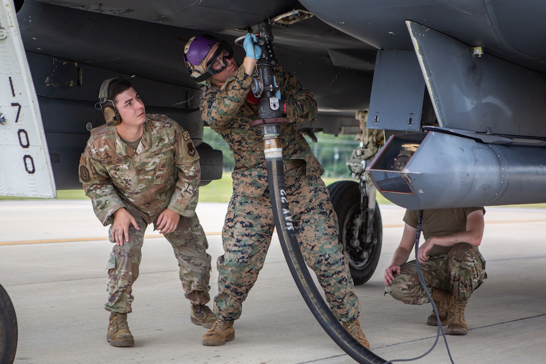 U.S. Air Force Staff Sgt. Ethan Tentler (left) and Senior Airman Nathan Jester (right), quality-assurance Airmen with 4th Fighter Readiness Squadron, observe U.S. Marine Corps Cpl. Lance Flinchum, a bulk-fuel specialist with Marine Wing Support Squadron (MWSS) 272, as he refuels an F-15E Strike Eagle at Seymour Johnson Air Force Base, North Carolina, Aug. 16, 2022. The Marines and Airmen trained in aircraft refueling to enhance interoperability for future joint expeditionary advanced base operations. MWSS-272 is a subordinate unit of 2nd Marine Aircraft Wing, the aviation combat element of II Marine Expeditionary Force. (U.S. Marine Corps photo by Pfc. Rowdy Vanskike)