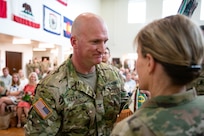 A soldier receives organizational colors from another soldier