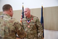 Two soldiers shake hands after one of them receives an award