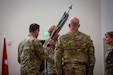 Four soldiers face each other and pass a flag to each other.