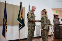 two soldiers shake hands in front of an audience at a change-of-command ceremony.