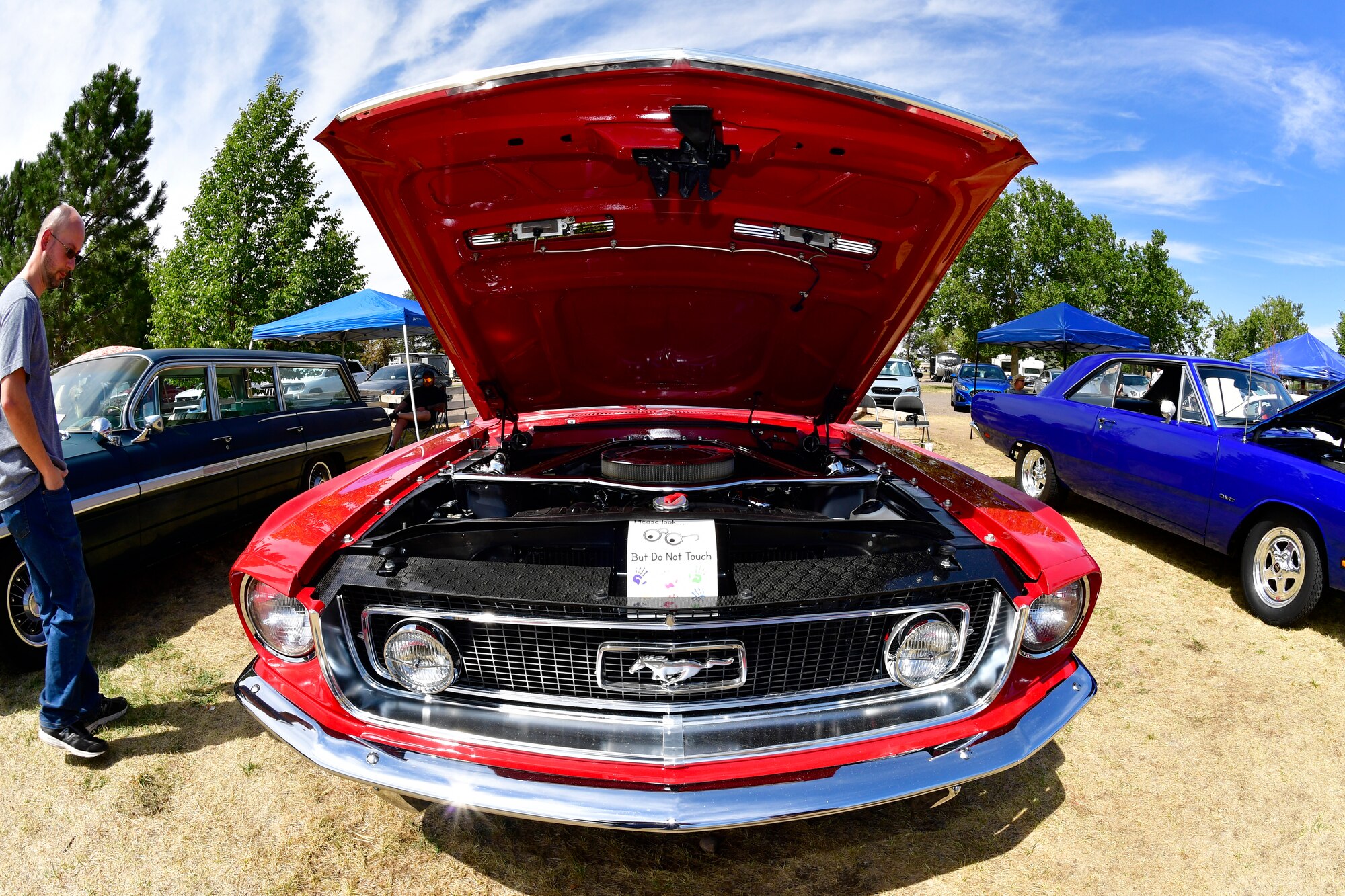 The engine under the hood of a red 1968 Ford Mustang