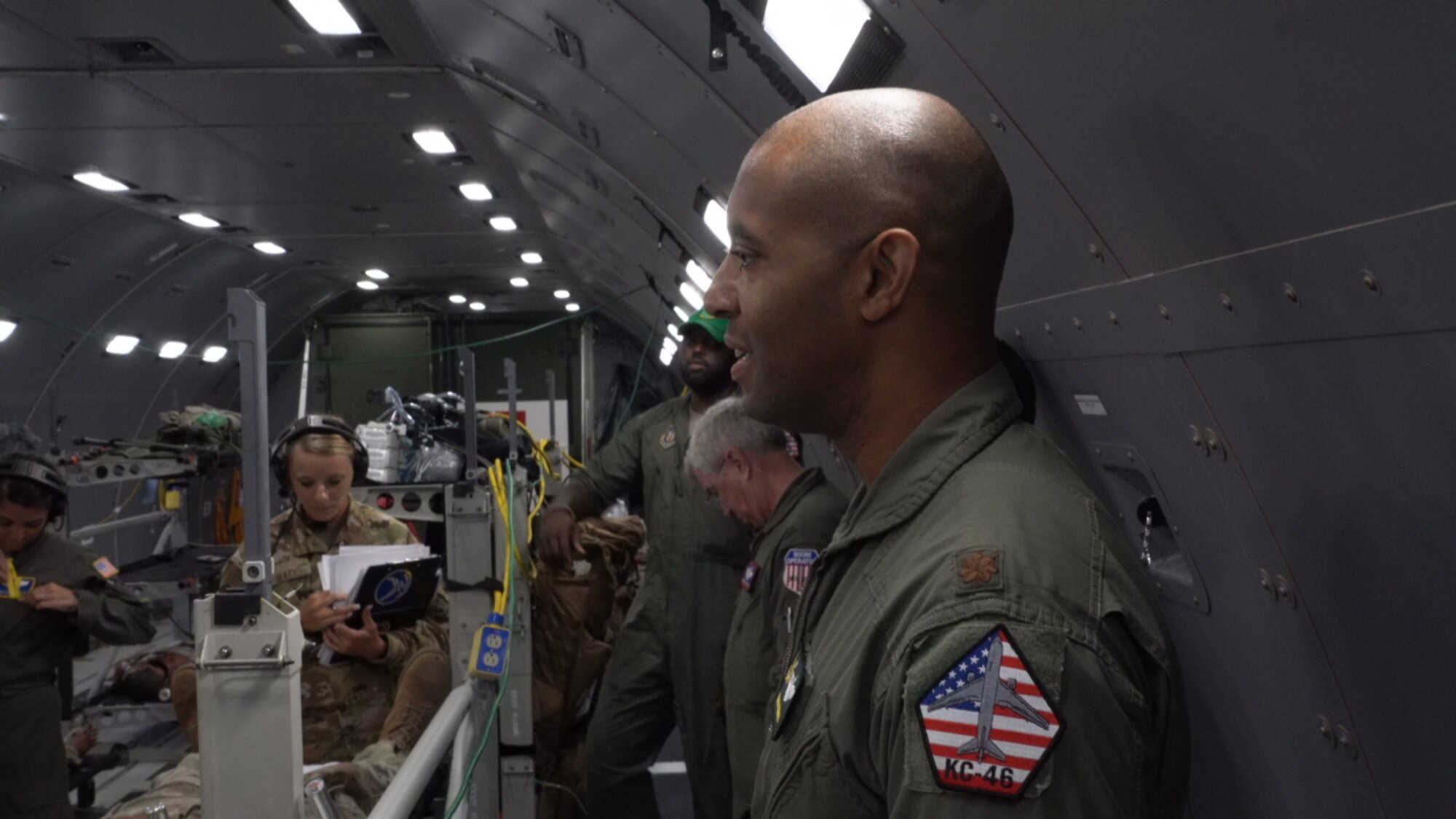 The aircraft commander stands next to wall of the aircraft briefing all of the aeromedical personnel on the plane.