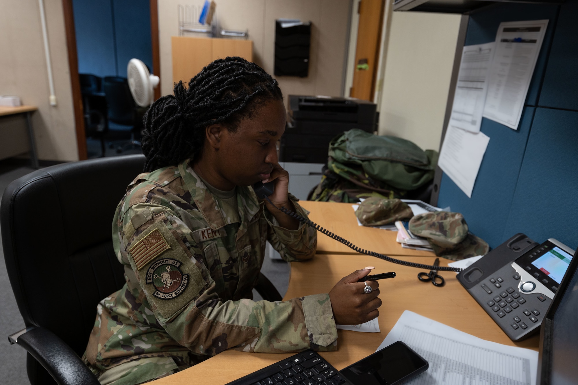 An Airman picks up the phone and listens to the caller.