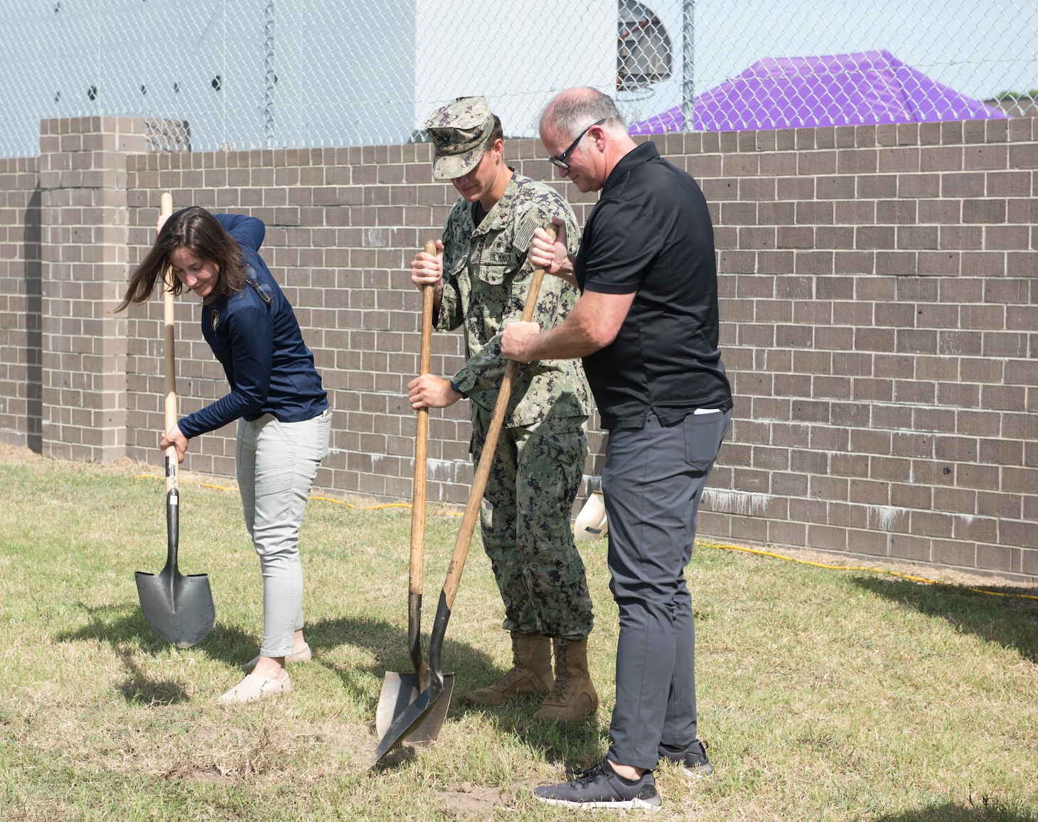 Suzanna Fisher, executive director at Navy Special Operations Foundation, Navy Diver Seaman Chris Pedrini, and Henry Thrift, president of Navy Explosive Ordnance Disposal Association, dig during the groundbreaking ceremony for the Navy Special Operations Memorial.