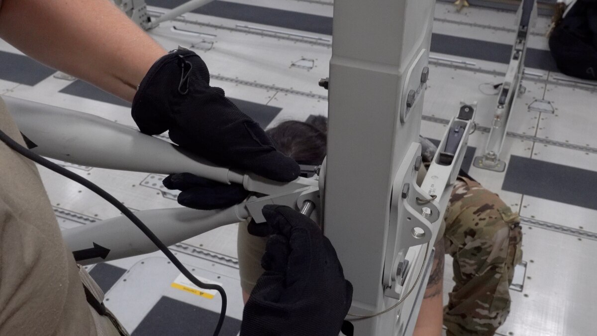Hands showing the connections holding the litter stantion sets being put together.
