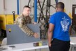 Tech. Sgt. Trenton Johnson, 193rd Special Operations Maintenance Squadron aircraft structural craftsman, describes to a right start member how he places a hole patch on a panel during a career fair in Middletown, Pa., August 6, 2022. The wing hosted the career fair to allow Airmen to see different career fields and learn about their capabilities in hopes of cultivating a community atmosphere.
