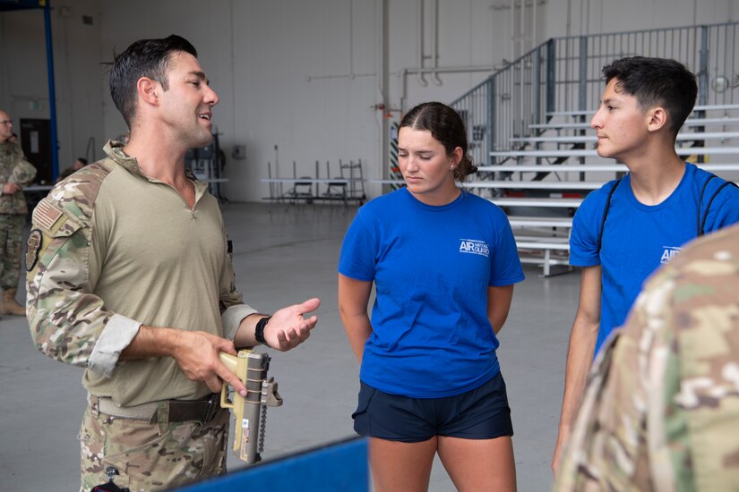 Tech. Sgt. Zachary Holder, left, 193rd Special Operations Squadron tactical air control party, shows right start members a hand-held laser marker during a career fair in Middletown, Pa., August 6, 2022. The wing hosted the career fair to allow Airmen to see different career fields and learn about their capabilities in hopes of cultivating a community atmosphere.
