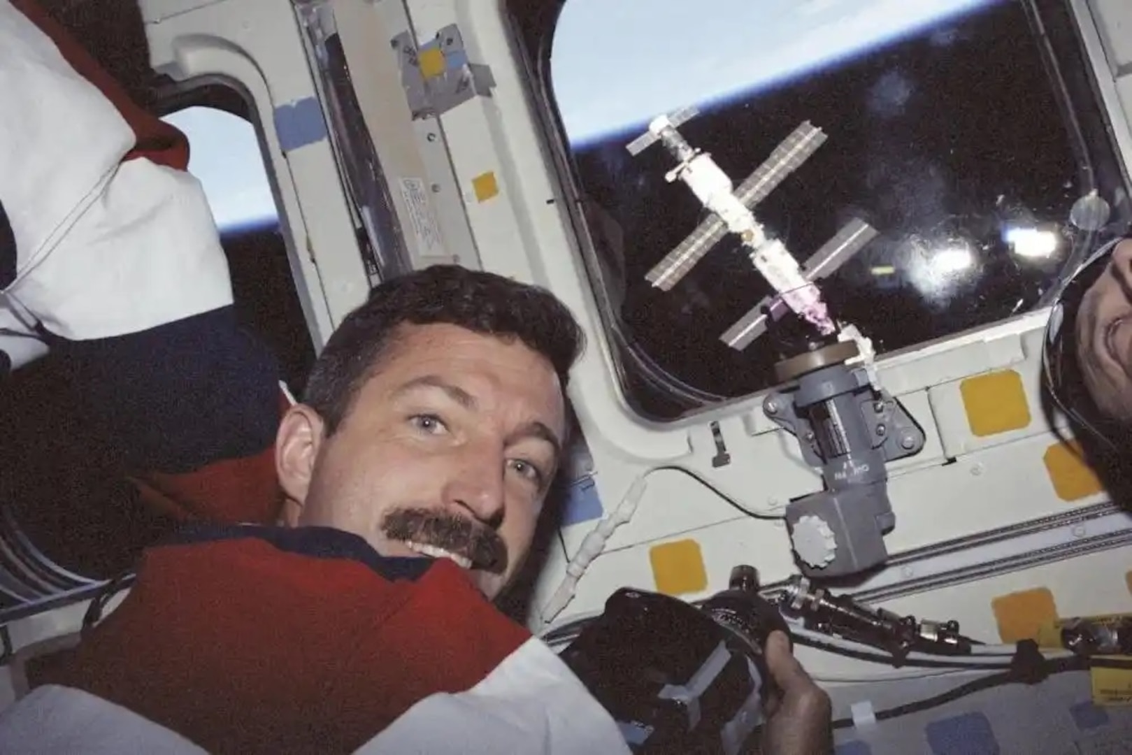 Astronaut Daniel C. Burbank, mission specialist, prepares to photograph the International Space Station through the overhead windows on the aft flight deck of the Space Shuttle Atlantis. Burbank is returning to the U.S. Coast Guard Academy to serve as a Professor of Practice in the Mechanical Engineering program.