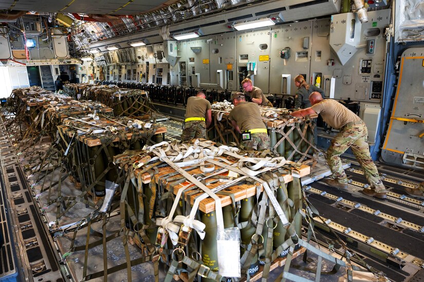 Airmen push and load pallets of ammunition into a C-17 Globemaster III.