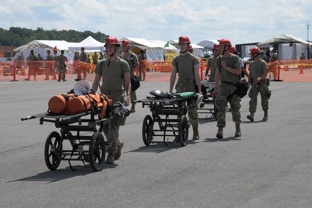 A line of soldiers push gurneys carrying supplies.