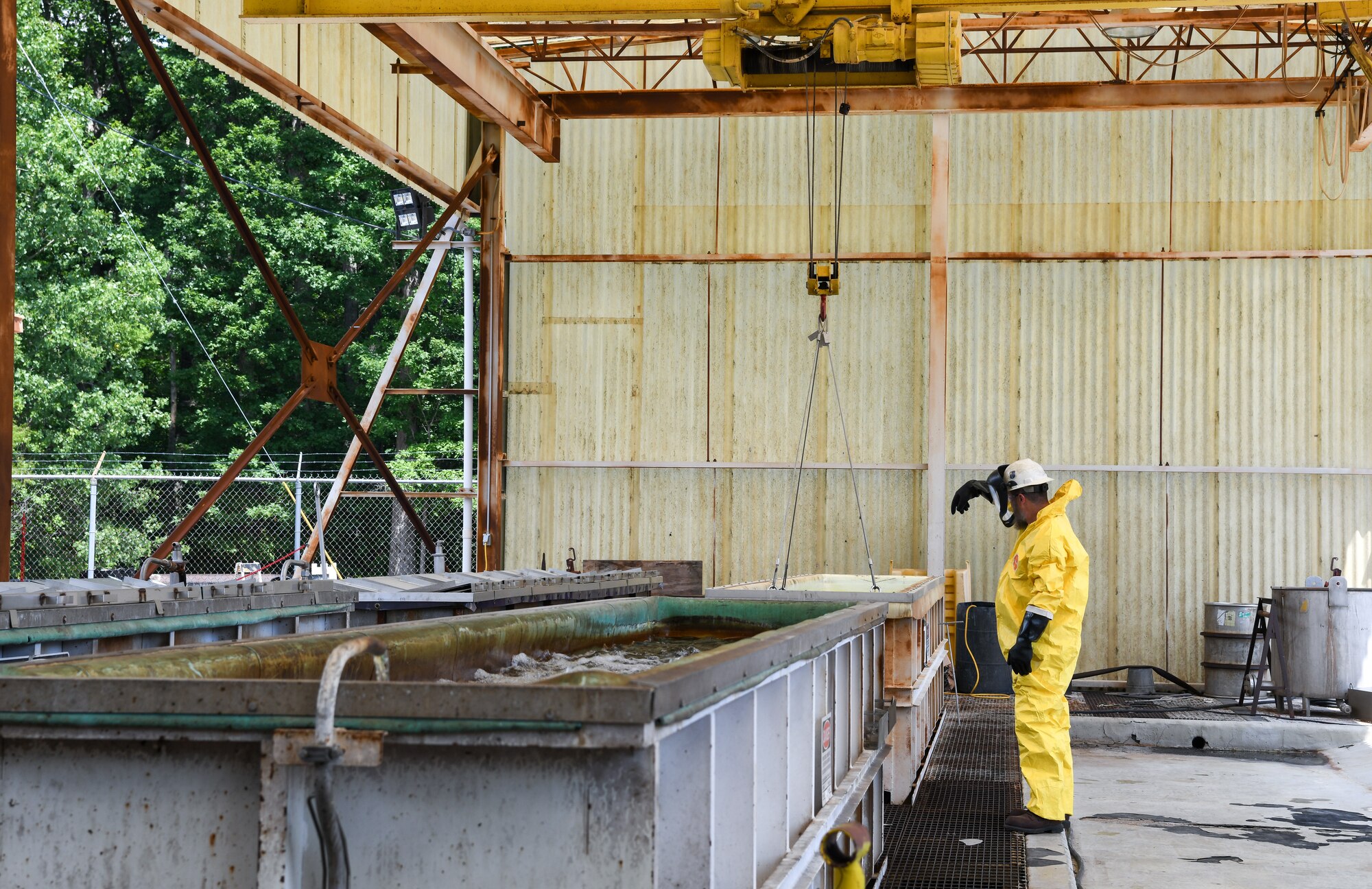 Worker in yellow Tyvek suit directing crane operations