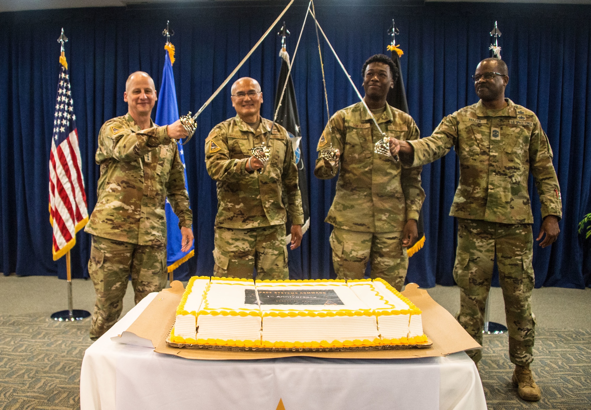 SSC Commander, Lt. Gen. Michael A. Guetlein (left) and SSC Senior Enlisted Leader, CMSgt Willie H. Frazier II (right), conduct a ceremonial cake cutting with the oldest and youngest member of the command. Space Systems Command commemorated its one-year anniversary of as a USSF Field Command, at Los Angeles Air Force Base, El Segundo, Calif., August 12, 2022. (U.S. Space Force photo by Van Ha)