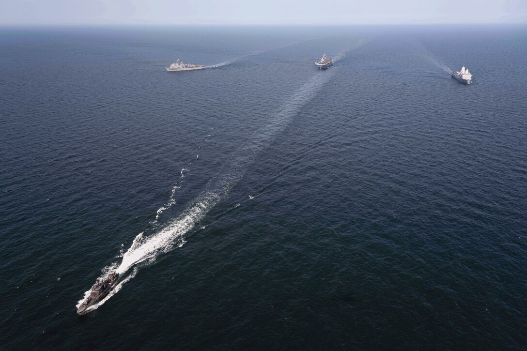 Four U.S. and Finnish naval ships sail in formation in a body of water.