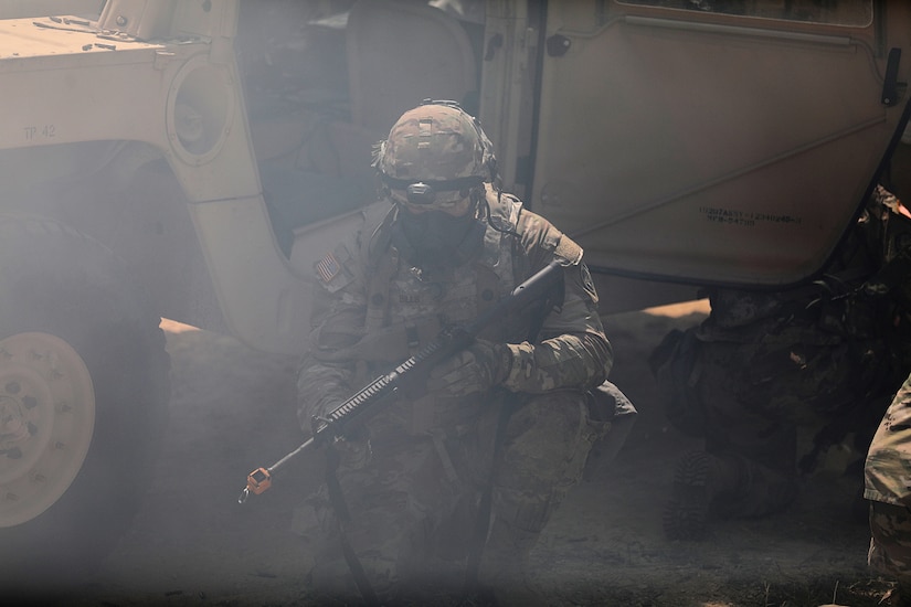A U.S. Army Reserve Soldier, shielded by a High Mobility Multi-Purpose Wheeled Vehicle, prepares to return fire on insurgents during a complex simulated indirect fire attack with Chemical, Biological, Radiological, and Nuclear agents during convoy operations lane training at the CSTX 86-22-02 at Fort McCoy, Wisconsin, August 16, 2022.