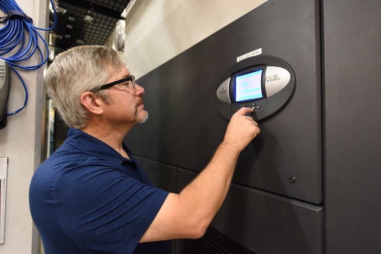 Matt Dodds, 21st Communications Squadron infrastructure branch chief, examines settings on the Communication Room Air Conditioning unit located inside a server room on Peterson Space Force Base, Colorado, Aug. 12, 2022.