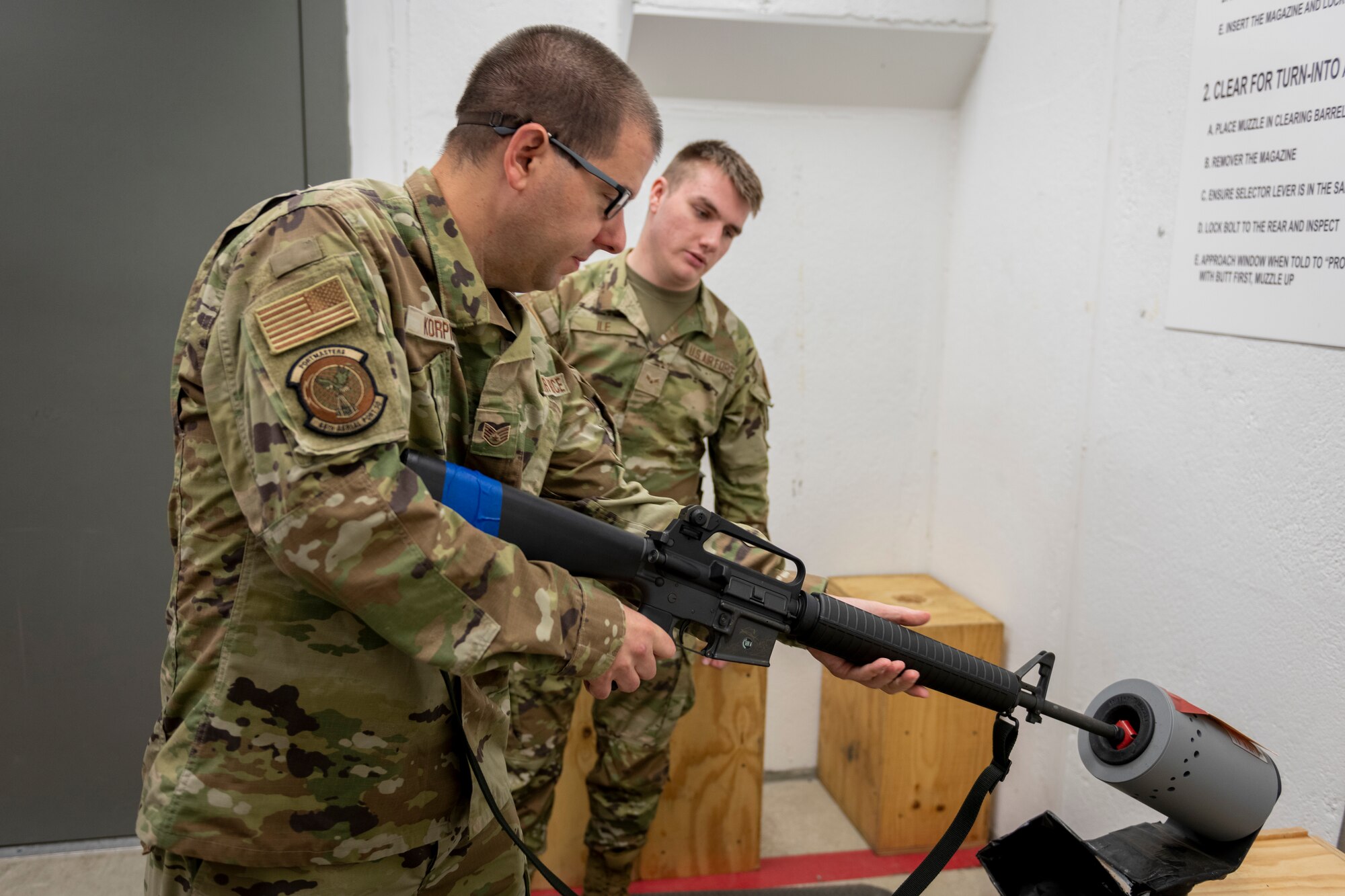 U.S. Air Force Airman 1st Class Cody Ile, 436th Logistics Readiness Squadron, Dover Air Force Base, Del., watches Staff Sgt. Jeffrey Korpics, 46th Aerial Port Squadron, clear an issued M16 rifle Aug. 14, 2022.  Reserve aerial porters from the 512th Airlift Wing, participated in a week-long Joint Readiness Training Center exercise at Fort Polk, La. JRTC scenarios allow complete integration of Air Force and other military services as well as host-nation and civilian role players. The exercises replicate many of the unique situations and challenges a unit may face including host-national officials and citizens, insurgents and terrorists, news media coverage, and non-governmental organizations. (U.S. Air Force photo by Senior Airman Ruben Rios)