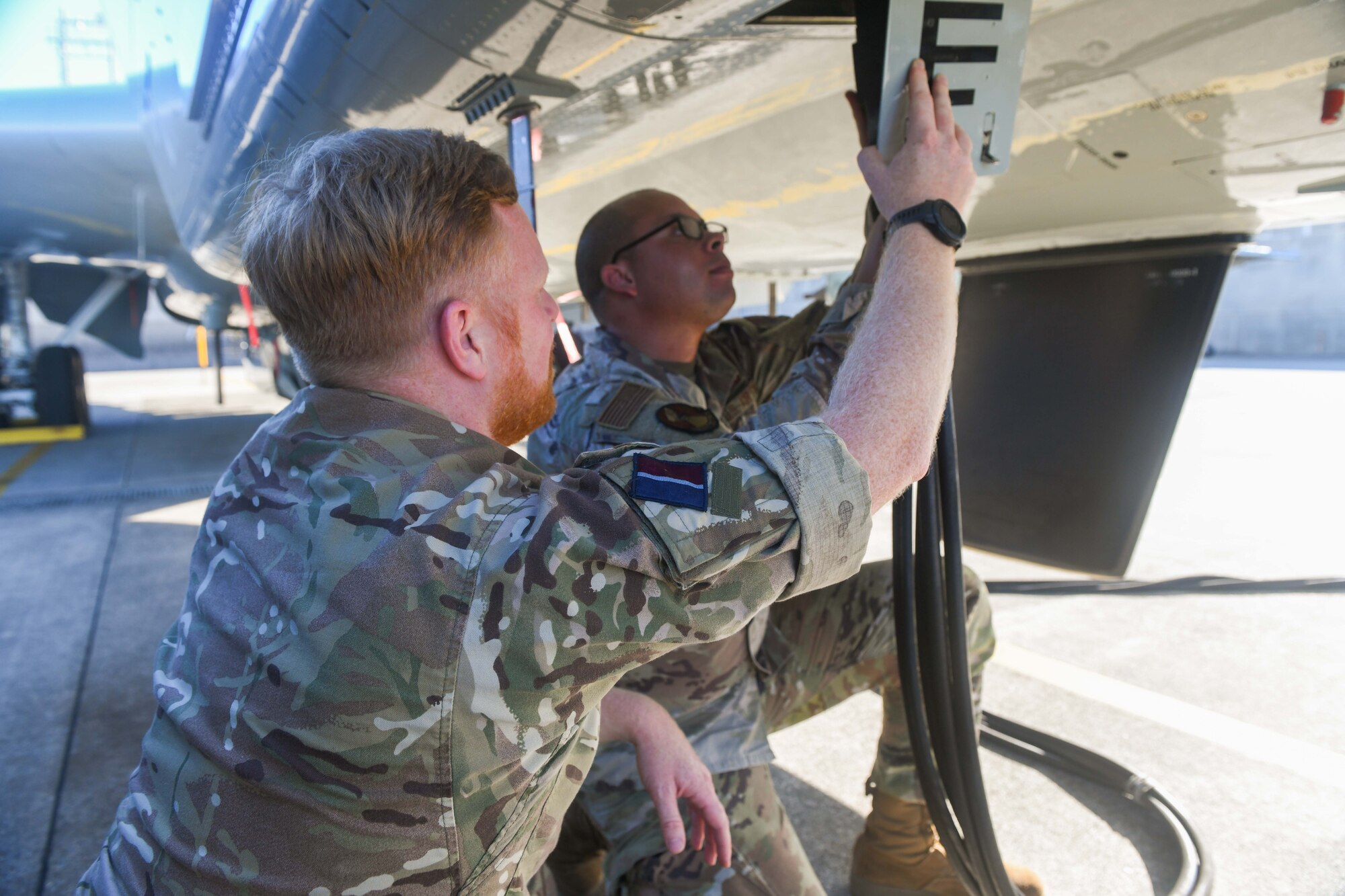 Airman and aviator hook a power source to an aircraft.