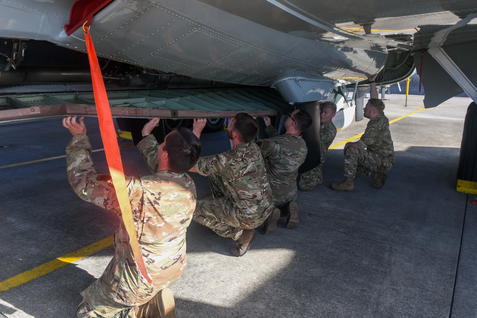 Airmen and aviators work together on an aircraft.