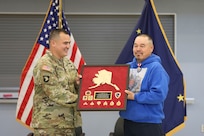 Alaska Army Guard Maj. Walter Hotch-Hill, 49th Missile Defense Battalion (Ground-based Midcourse Defense), presents a gift to 1st Class Joseph Sallaffie, 1st Battalion, 297th Infantry Regiment, during a retirement ceremony at the National Guard armory in Bethel, Aug. 19, 2022.