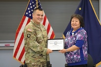 Alaska Army Guard Maj. Walter Hotch-Hill, 49th Missile Defense Battalion (Ground-based Midcourse Defense), presents Rachel Sallaffie with a certificate of appreciation for her support to the organization during a retirement ceremony for her husband, Sgt. 1st Class Joseph Sallaffie, at the National Guard armory in Bethel, Aug. 19, 2022.